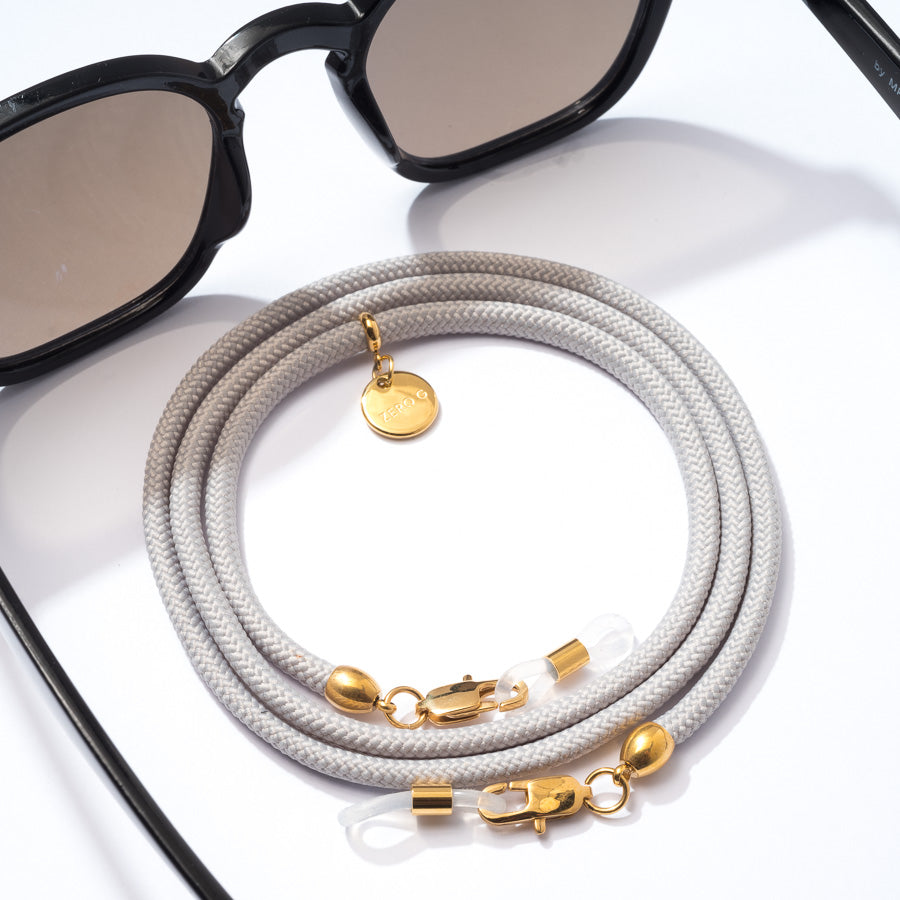 Sonnenbrille mit hellgrauen Brillenband und goldenen Metall Elementen