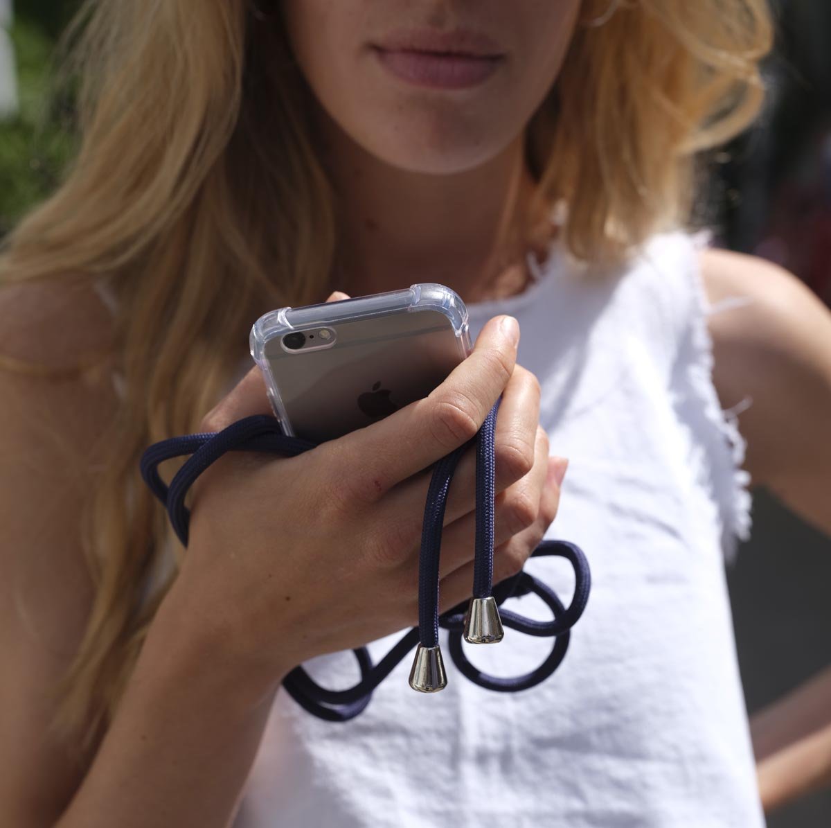 Frau hält iPhone mit dunkelblauer Handykette in der Hand.