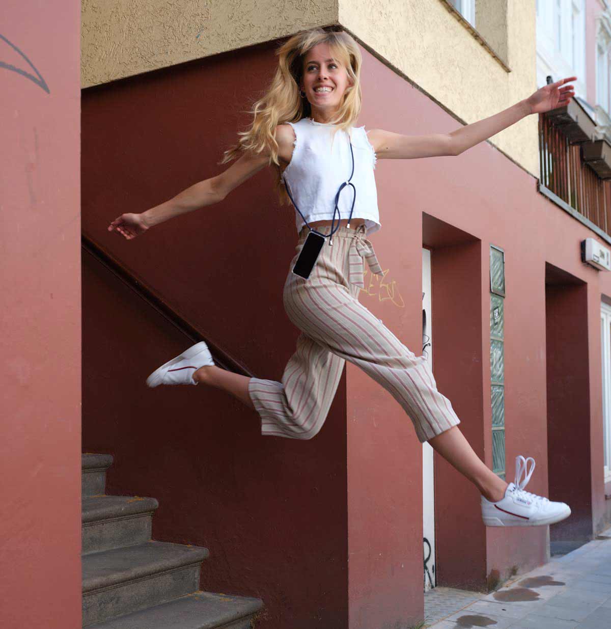 Blonde Frau mit handykette springt von einer Treppe