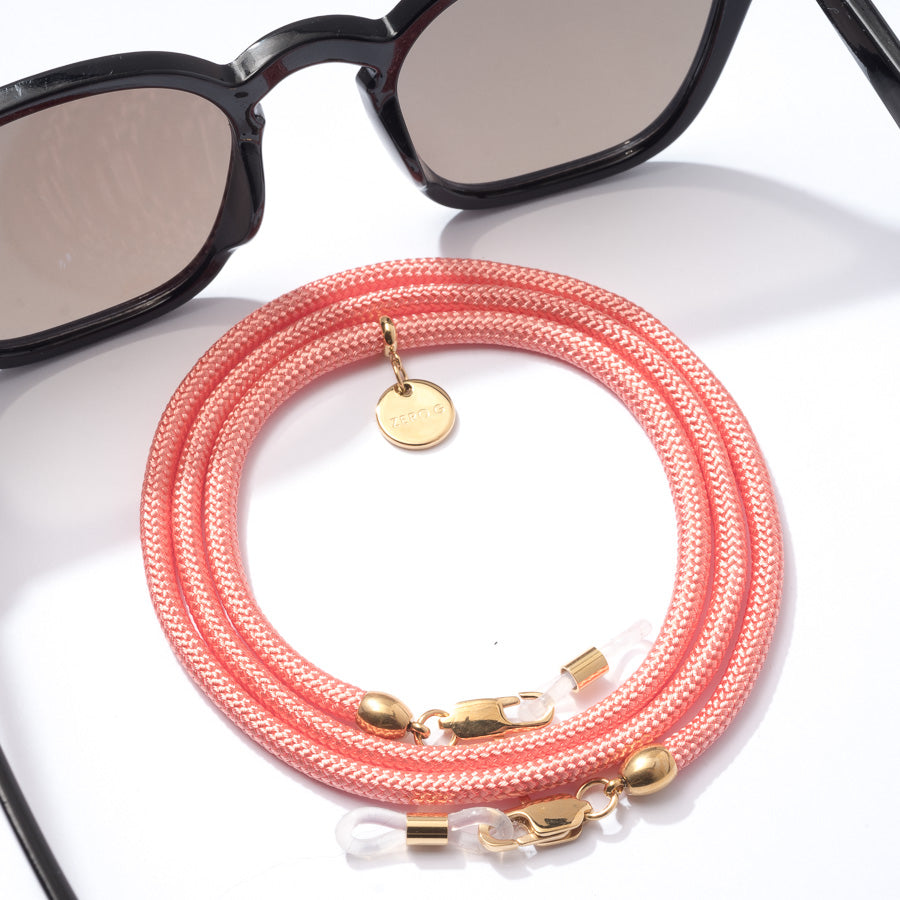 Sonnenbrille mit korall-pinkem Brillenband und goldenen Metall Elementen