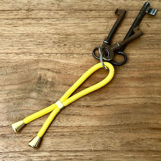 Gelber Schlüsselanhänger mit goldenem Slider und Endstücken befestigt an alten Schlüsseln.