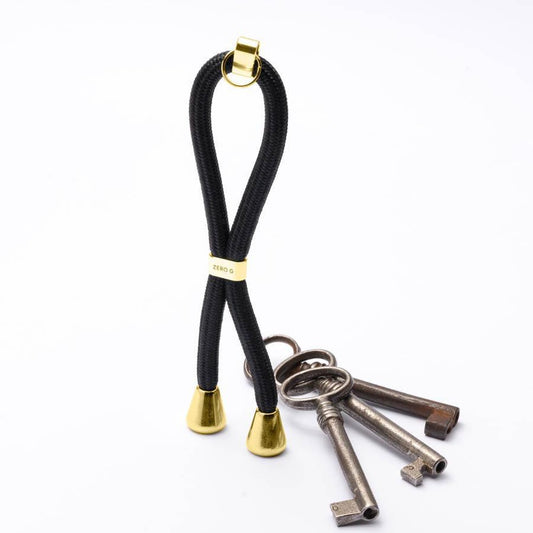 Glänzend schwarzer Schlüsselanhänger mit goldenem Slider und Endstücken.